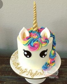 a birthday cake decorated with an unicorn's face and rainbow manes on top