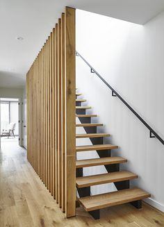 a wooden stair case next to a white wall