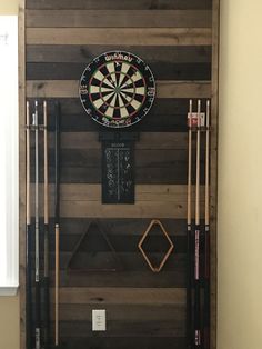 a dart board mounted to the side of a wall with darts and other items on it