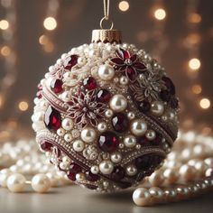 a christmas ornament with pearls and garnets on the table next to beads