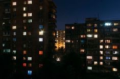 many windows are lit up at night in the building's dark, city - like surroundings