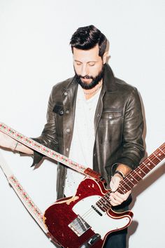 a man with a beard holding an electric guitar