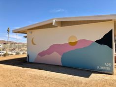 a large mural on the side of a building with mountains and sun in the background