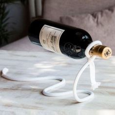 a bottle of wine is hooked up to a cord on a marble table top with a couch in the background