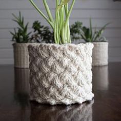 two crocheted planters sitting on top of a table next to each other