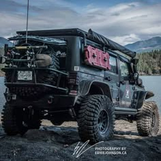 a black jeep parked on the side of a lake