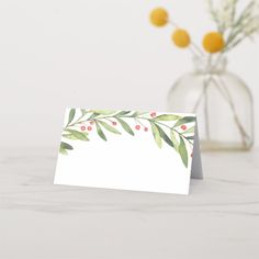 a card with watercolor leaves and berries on it next to a vase filled with flowers