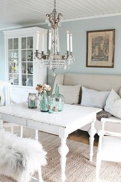 a living room filled with furniture and a chandelier above a white coffee table