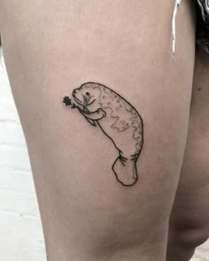 a woman's thigh with a small tattoo of a fish holding a flower on it