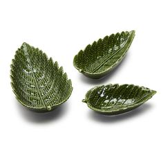 three green leaf shaped dishes on a white surface