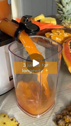 a blender filled with oranges and juice on top of a table next to other fruits