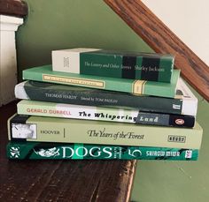 a stack of books sitting on top of a wooden table next to a stair case