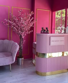 a pink and gold reception desk in a room with two chairs next to each other