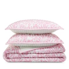 three pillows stacked on top of each other in front of a white background with pink and white designs