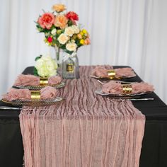 the table is set with black and pink linens, gold place settings, and flowers