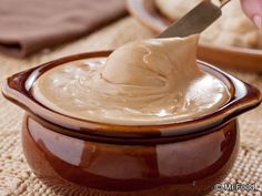 a person is spreading icing on top of some food in a brown bowl with a spoon