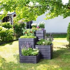 four wooden planters with different types of flowers in them on the grass near a house