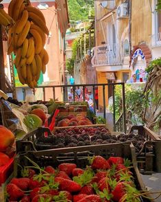 several trays of strawberries and other fruit on display in front of a building