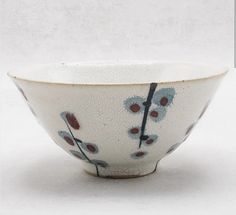 a white bowl with blue and red flowers on it's rim, against a white background