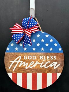 a wooden sign with the words god bless america on it and an american flag bow