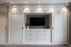 an entertainment center with white cabinets and a flat screen tv mounted on it's wall