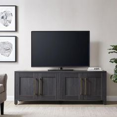 a flat screen tv sitting on top of a wooden entertainment center in a living room