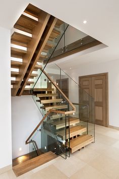 a staircase with glass railing and wooden handrails in a modern style home setting