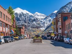 a street with cars parked on both sides and mountains in the background