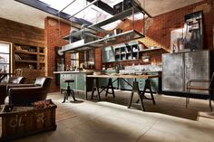 an industrial style kitchen with brick walls and steel appliances on the countertop, along with two stools