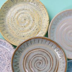 four ceramic plates sitting on top of each other in different colors and sizes, all with spiral designs