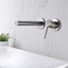 a white sink sitting under a faucet next to a wall mounted soap dispenser