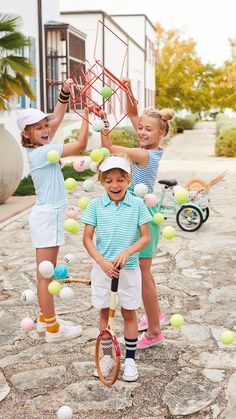 three young children are playing with tennis balls