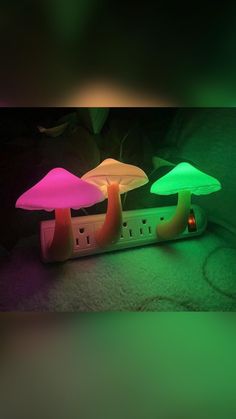 two mushroom shaped lights sitting on top of a power strip in front of a plant