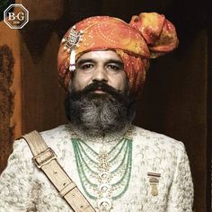 a man with a beard wearing an orange turban and holding a green belt