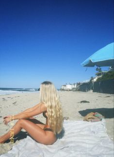 a woman sitting on top of a sandy beach