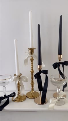 three candles are sitting on a table with black and white ribbons tied around the candle holders