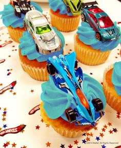 cupcakes with blue frosting and cars on them are sitting on a table