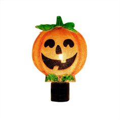 an orange pumpkin shaped light on top of a black holder