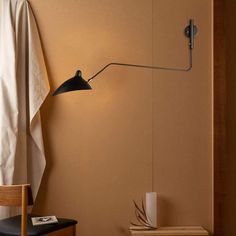 a lamp that is on the side of a wall next to a chair and table