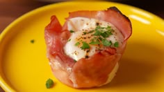 a yellow plate topped with an egg and bacon muffin