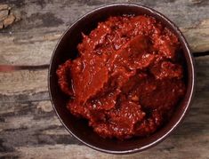 a bowl filled with red sauce sitting on top of a wooden table