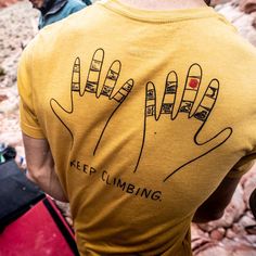 a man wearing a yellow t - shirt with the words keep climbing written on it