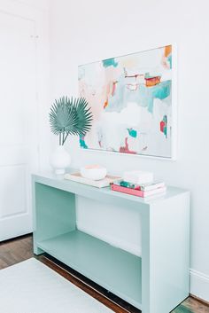 a green console table with books and a plant on top