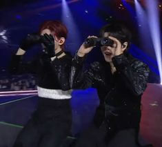 two people standing next to each other with their hands in the air and one person looking through binoculars