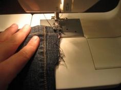 someone is using a sewing machine to sew something on the side of their jeans