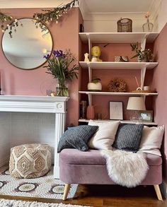 a living room filled with furniture and a fire place in front of a pink wall