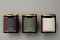 three jars with labels on them sitting side by side in front of a gray background