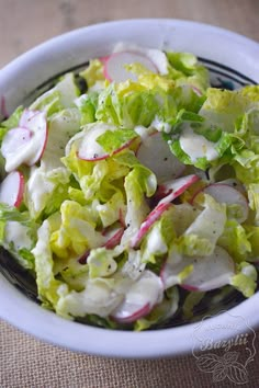 a salad with radishes and cheese in a white bowl on a brown table