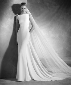 a woman in a wedding dress standing next to a wall with her veil pulled back