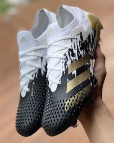 someone is holding up their new adidas soccer cleats with gold and black paint splattered on them